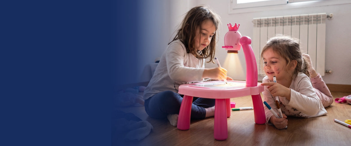 Dos niñas dibujando juntas en la mesita con proyector rosa, en el suelo de casa