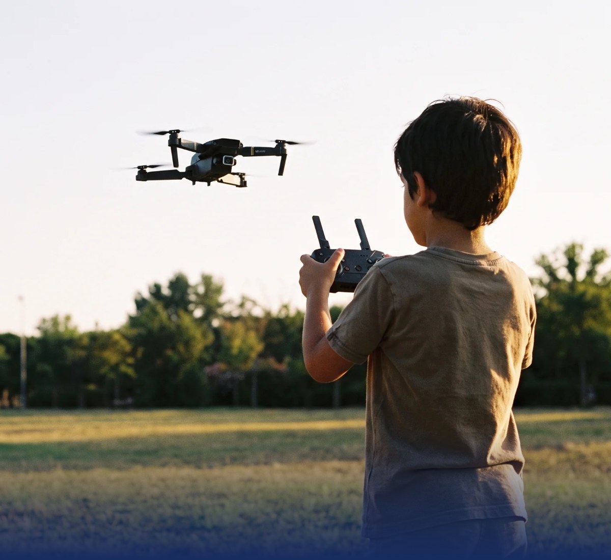 Niño volando el dron en el parque al atardecer