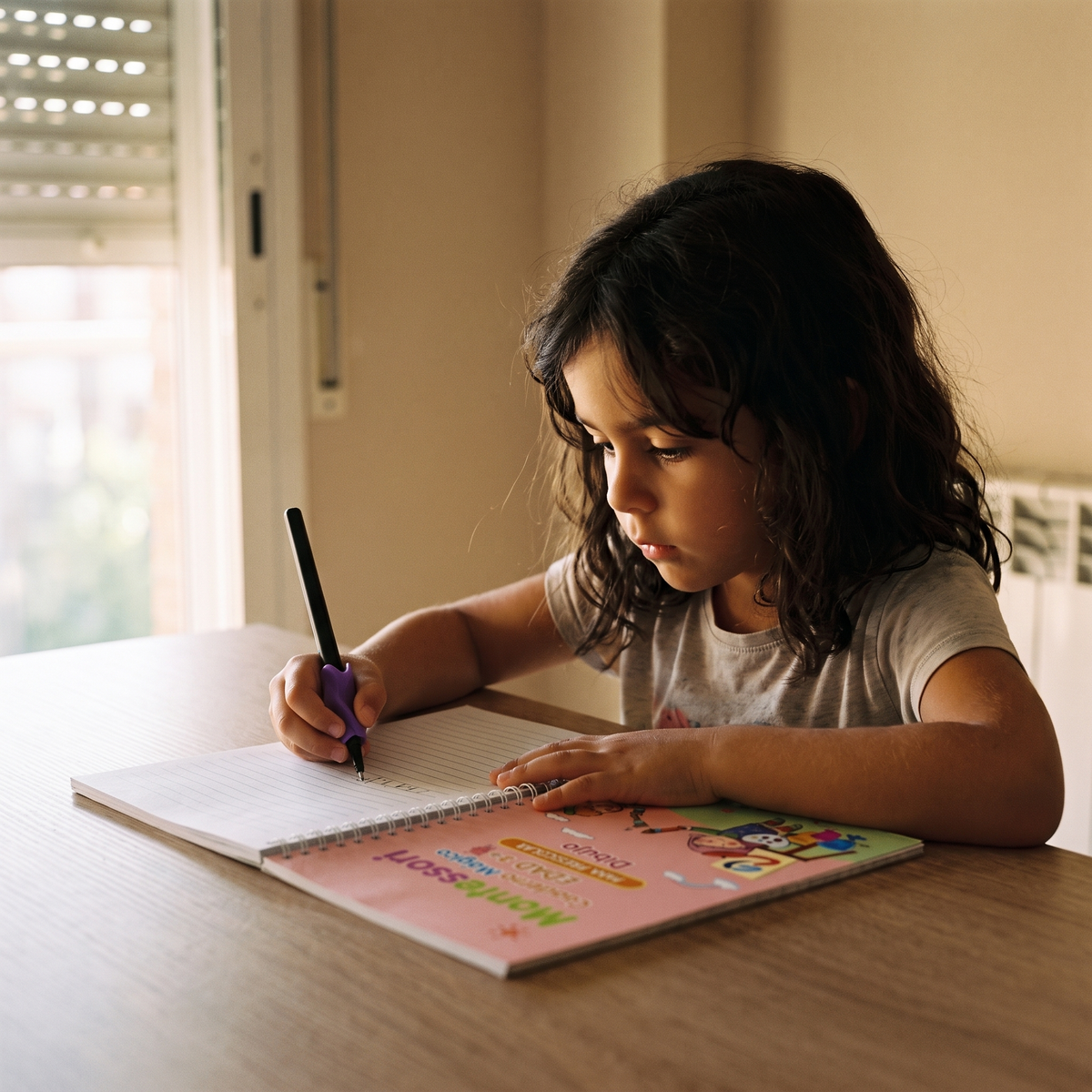 Niña escribiendo en el cuaderno mágico en la mesa del comedor